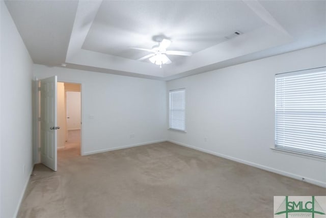 unfurnished bedroom with a raised ceiling, light carpet, and ceiling fan