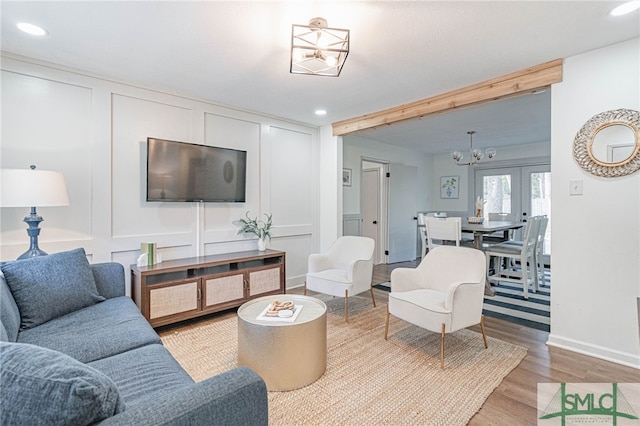 living room with hardwood / wood-style floors, an inviting chandelier, and french doors