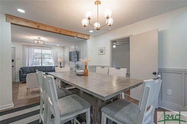 dining area with ceiling fan with notable chandelier, a textured ceiling, and dark wood-type flooring