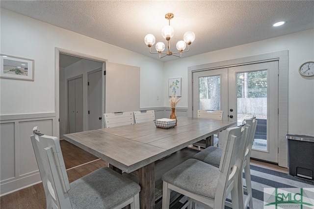 dining room featuring dark hardwood / wood-style flooring, french doors, a textured ceiling, and an inviting chandelier