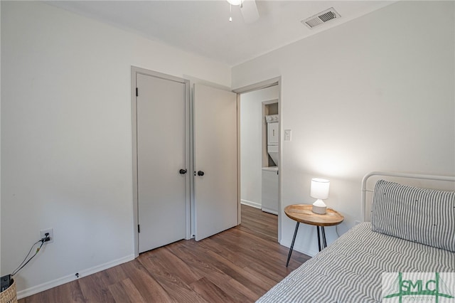 unfurnished bedroom with hardwood / wood-style flooring, ceiling fan, and stacked washer and clothes dryer