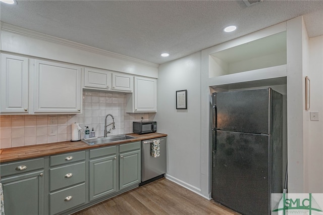 kitchen featuring sink, black appliances, light hardwood / wood-style floors, white cabinetry, and butcher block counters