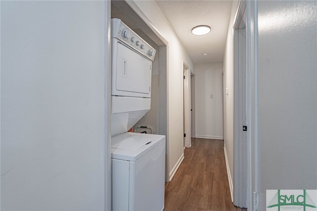 laundry room with hardwood / wood-style flooring and stacked washer / drying machine