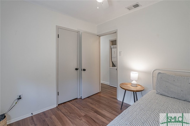 unfurnished bedroom featuring hardwood / wood-style floors, ceiling fan, and stacked washer and clothes dryer