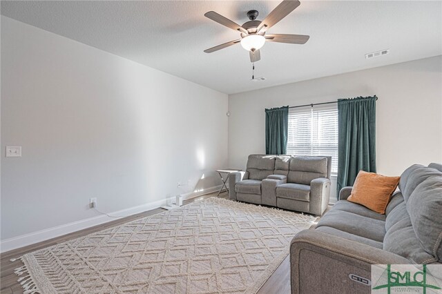 living room with ceiling fan, a textured ceiling, and hardwood / wood-style flooring