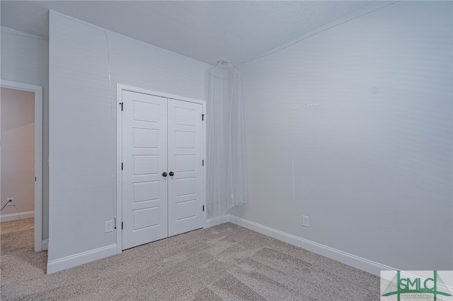 unfurnished bedroom featuring light carpet and a closet