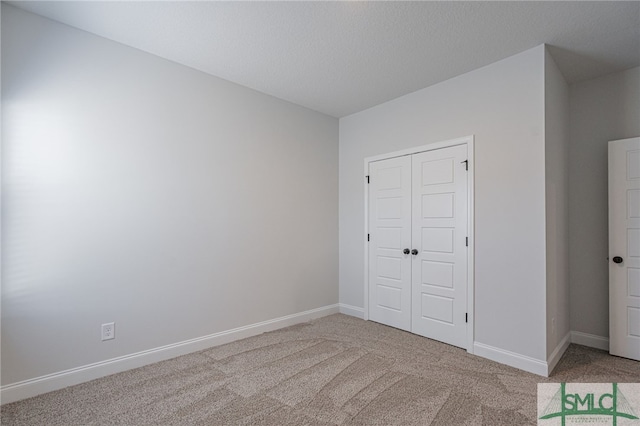 unfurnished bedroom with carpet flooring, a textured ceiling, and a closet