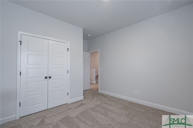 unfurnished bedroom featuring light colored carpet and a closet