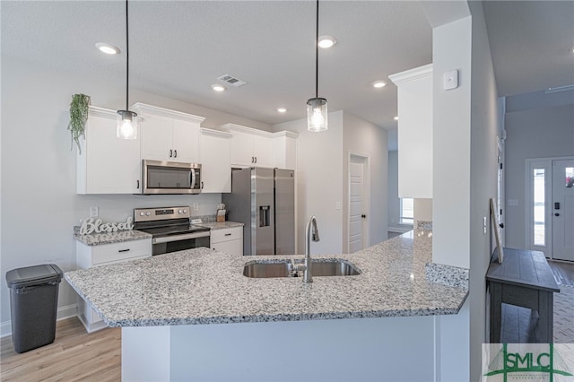 kitchen featuring white cabinets, decorative light fixtures, kitchen peninsula, and appliances with stainless steel finishes