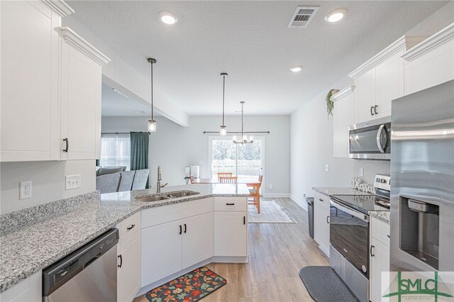 kitchen with pendant lighting, sink, light hardwood / wood-style floors, white cabinetry, and stainless steel appliances