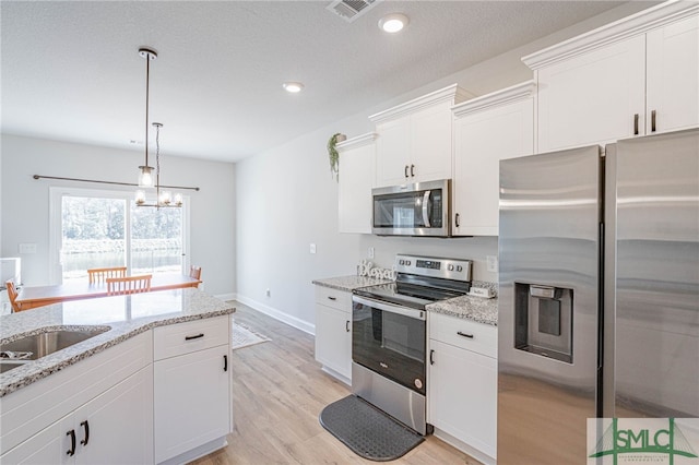 kitchen with light hardwood / wood-style floors, light stone countertops, white cabinetry, and appliances with stainless steel finishes