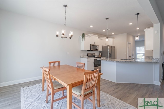 dining area with a chandelier, light hardwood / wood-style floors, and sink