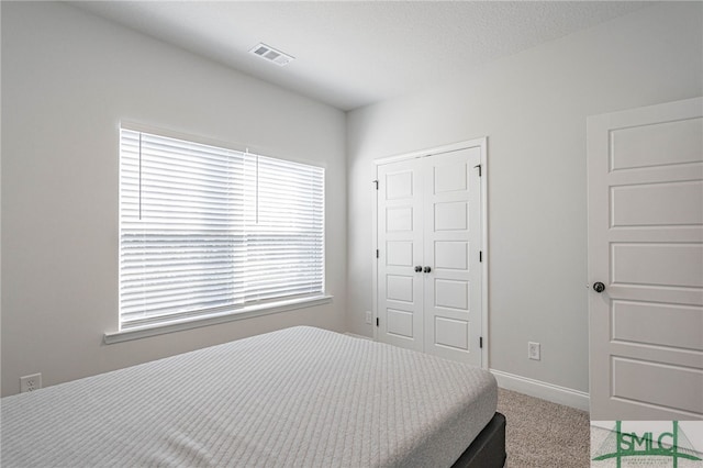 bedroom with light colored carpet, a textured ceiling, and a closet