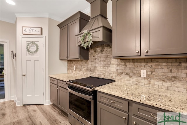 kitchen with backsplash, electric stove, ornamental molding, light hardwood / wood-style floors, and light stone counters