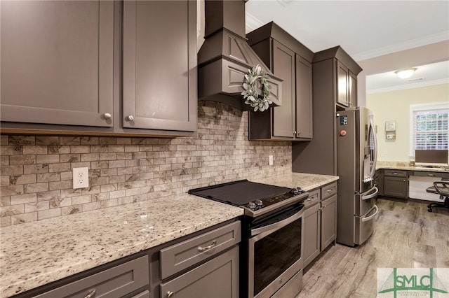 kitchen with crown molding, light hardwood / wood-style flooring, decorative backsplash, light stone countertops, and appliances with stainless steel finishes