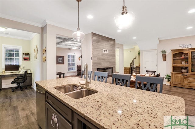 kitchen with light stone countertops, dark hardwood / wood-style flooring, hanging light fixtures, and sink