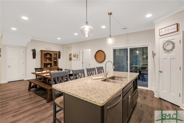 kitchen featuring pendant lighting, a center island with sink, sink, and dark wood-type flooring