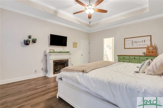 bedroom with a tray ceiling, crown molding, ceiling fan, and dark wood-type flooring