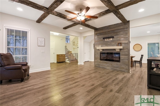 living room featuring hardwood / wood-style floors, coffered ceiling, ceiling fan, a fireplace, and beam ceiling