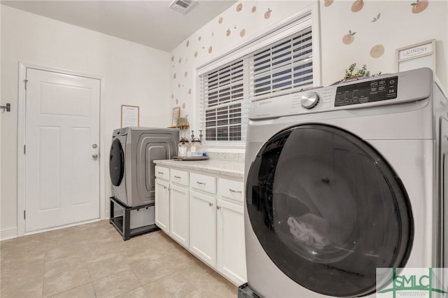 washroom with washer and dryer, cabinets, and light tile patterned flooring