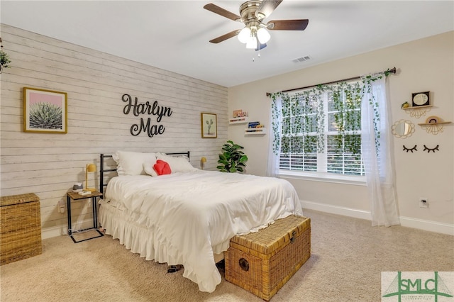 carpeted bedroom featuring ceiling fan and wooden walls