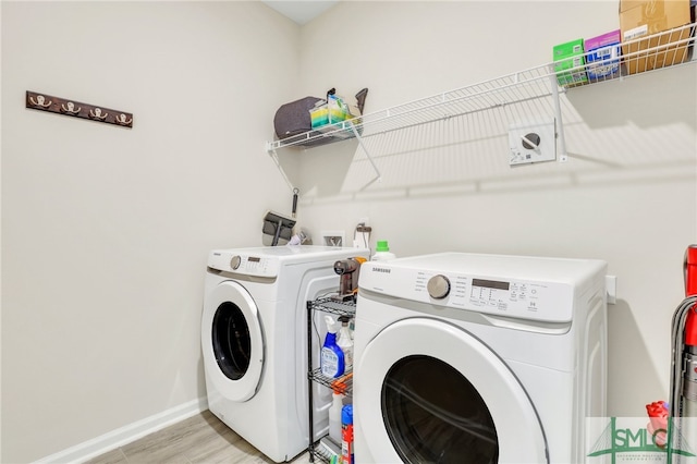 clothes washing area featuring separate washer and dryer and light hardwood / wood-style floors