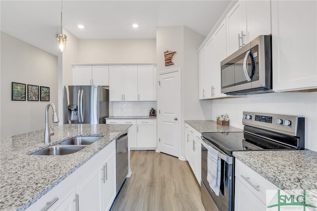 kitchen with sink, light hardwood / wood-style floors, pendant lighting, white cabinets, and appliances with stainless steel finishes