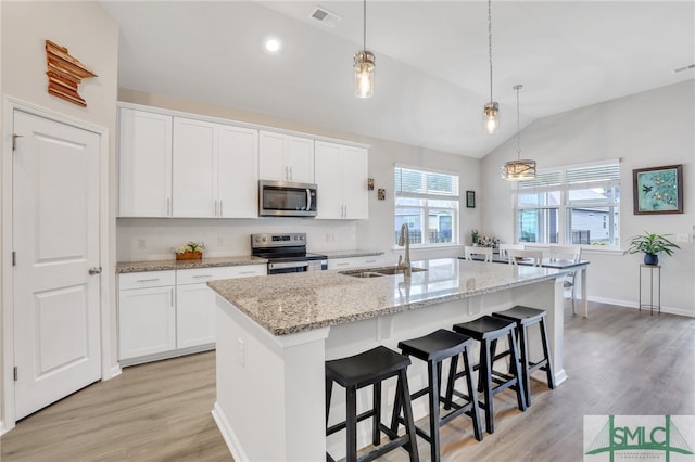 kitchen featuring a kitchen island with sink, white cabinets, sink, vaulted ceiling, and appliances with stainless steel finishes