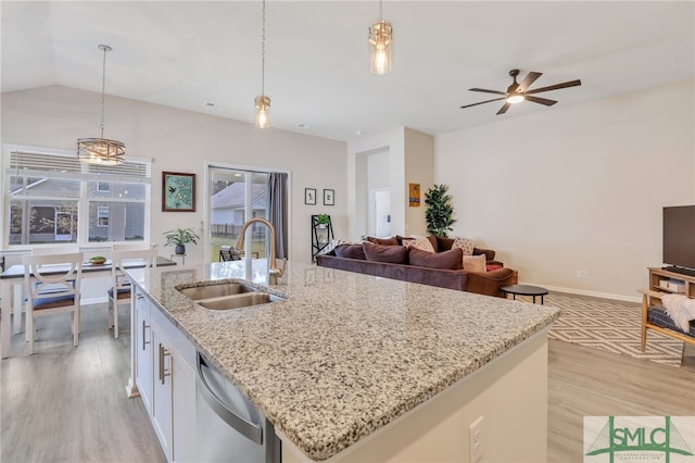 kitchen featuring sink, hanging light fixtures, stainless steel dishwasher, light wood-type flooring, and white cabinetry