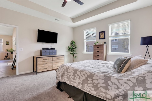 bedroom featuring light carpet, a raised ceiling, and ceiling fan