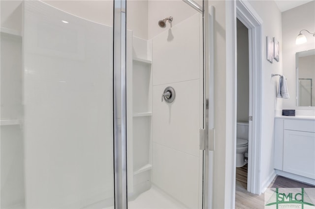 bathroom featuring hardwood / wood-style flooring, vanity, toilet, and walk in shower