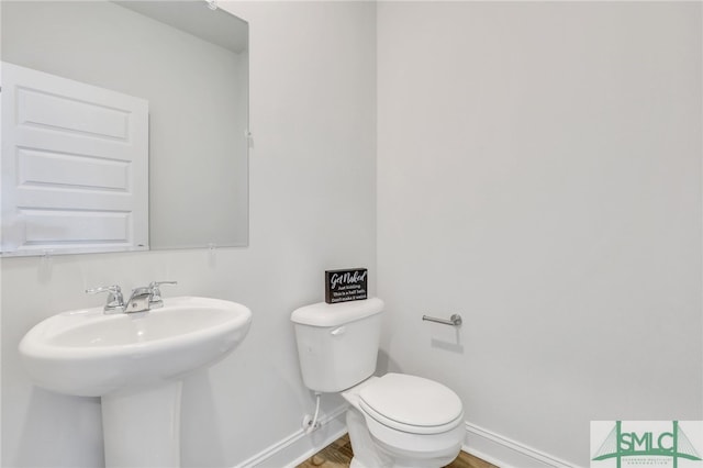 bathroom with wood-type flooring, toilet, and sink