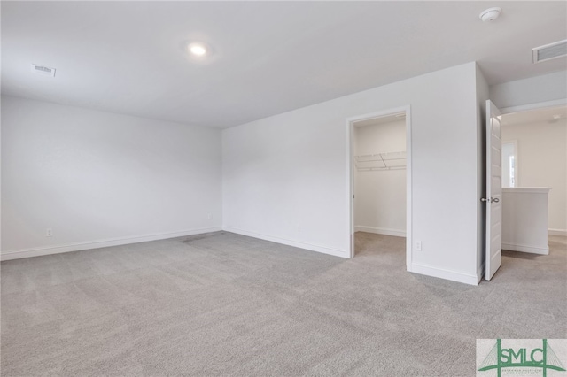 unfurnished bedroom with light carpet, a spacious closet, and a closet