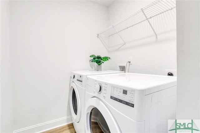 clothes washing area featuring washer and dryer and light hardwood / wood-style flooring