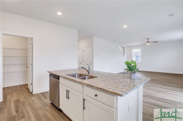 kitchen with white cabinetry, sink, stainless steel dishwasher, light hardwood / wood-style floors, and a center island with sink