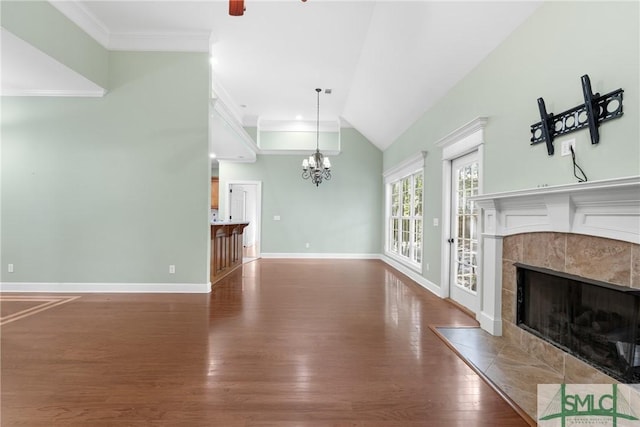 unfurnished living room with wood finished floors, crown molding, baseboards, a chandelier, and a tile fireplace