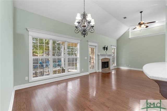 unfurnished living room with vaulted ceiling, a fireplace, baseboards, and wood finished floors