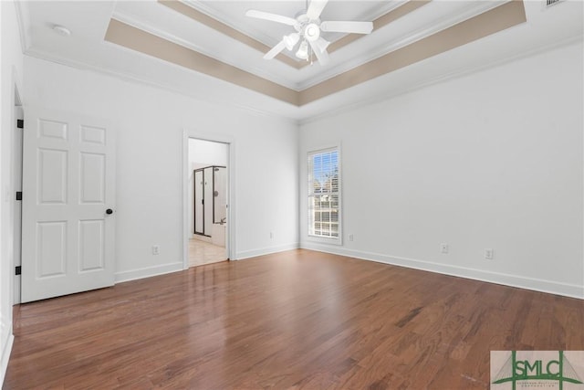 unfurnished room with a ceiling fan, a tray ceiling, wood finished floors, and ornamental molding