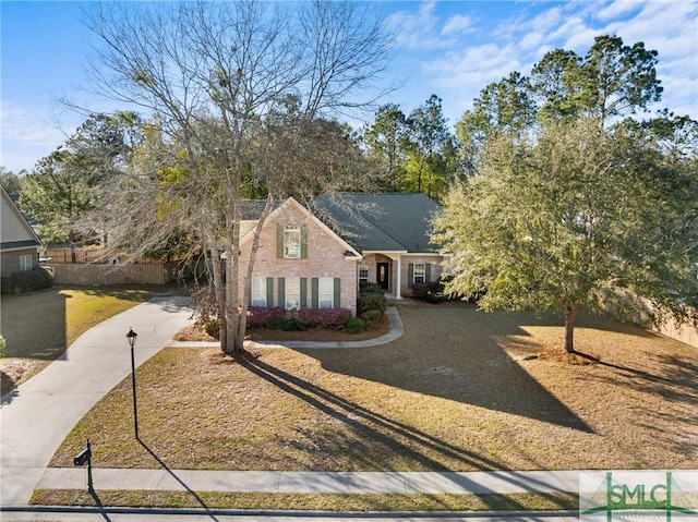 view of front of home with brick siding, driveway, and fence