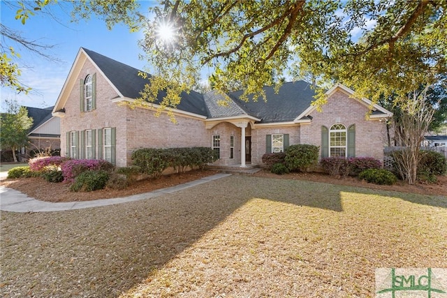 traditional-style house with brick siding and a front lawn