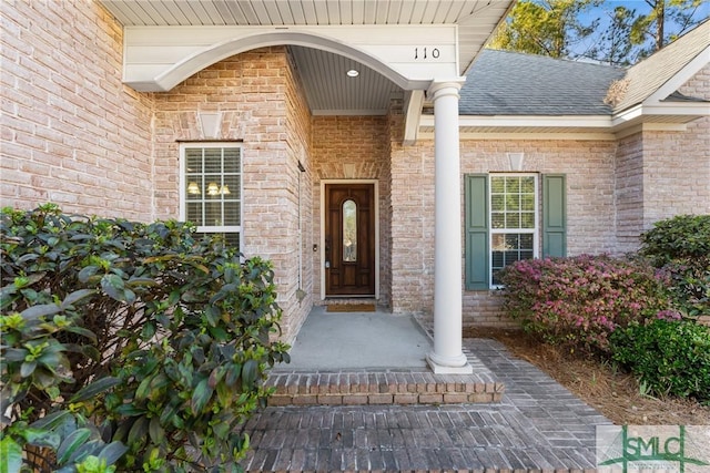 property entrance with brick siding and a shingled roof