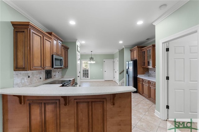 kitchen featuring a kitchen bar, light countertops, brown cabinets, a peninsula, and stainless steel appliances