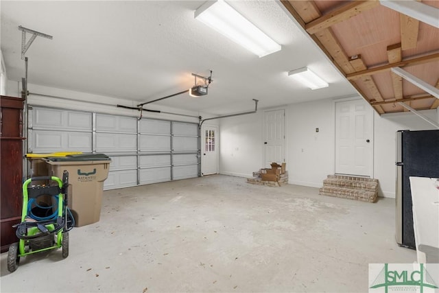 garage featuring baseboards, a garage door opener, and freestanding refrigerator