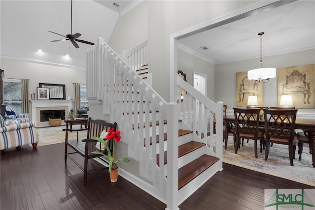 staircase featuring hardwood / wood-style floors, ceiling fan with notable chandelier, and ornamental molding