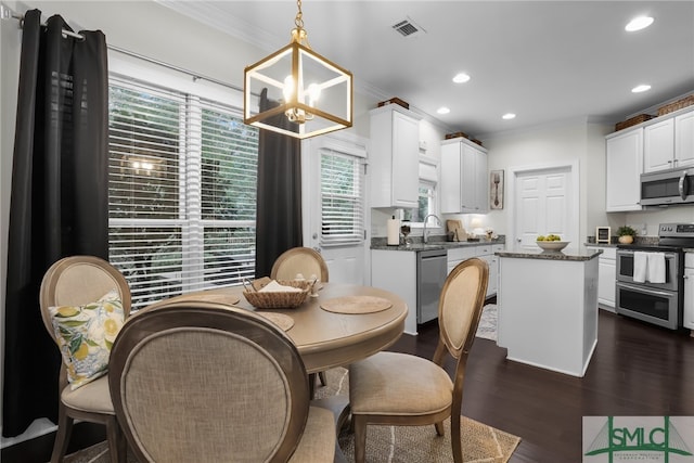 dining room featuring sink, dark hardwood / wood-style floors, crown molding, and a notable chandelier