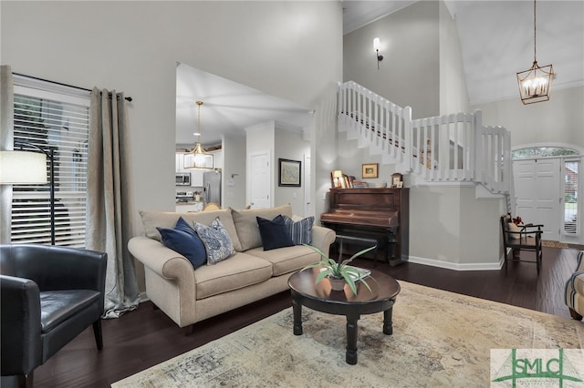 living room with a notable chandelier, dark hardwood / wood-style floors, crown molding, and high vaulted ceiling