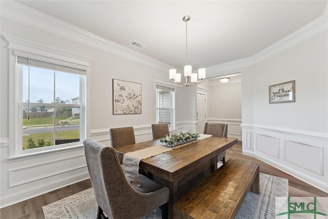 dining area featuring dark hardwood / wood-style flooring, crown molding, plenty of natural light, and an inviting chandelier