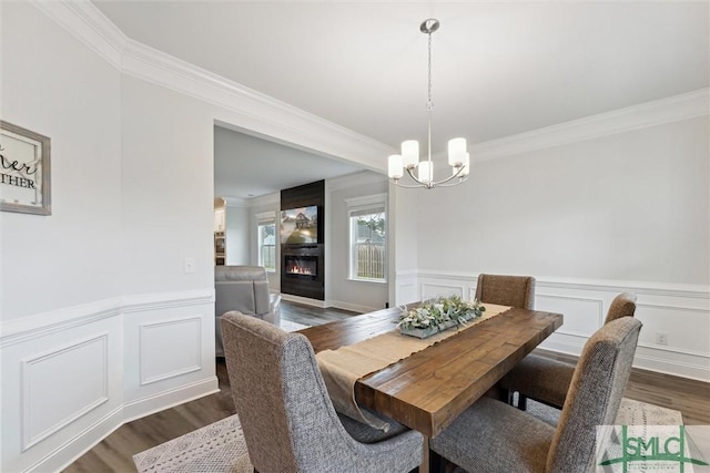 dining space featuring dark hardwood / wood-style floors, an inviting chandelier, and ornamental molding