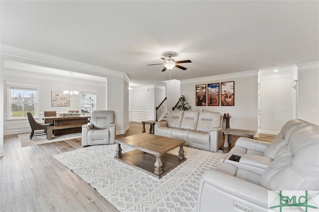 living room with ceiling fan with notable chandelier, light hardwood / wood-style floors, and ornamental molding