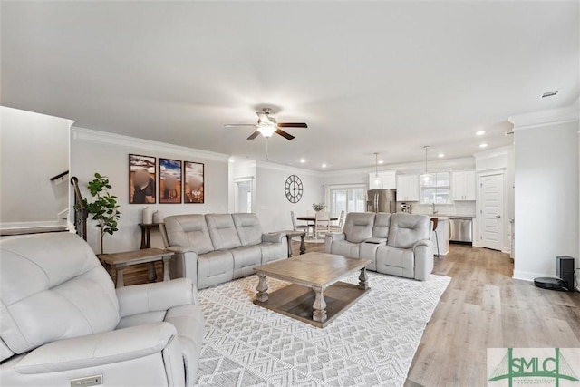 living room featuring light hardwood / wood-style floors, ceiling fan, crown molding, and sink